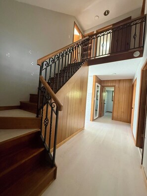A wooden staircase with black metal railings leading to an upper floor.