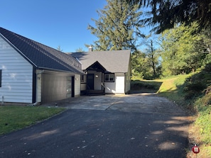 A two-story house with a garage, a covered porch, and a driveway leading to the entrance.