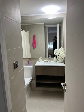 Une salle de bain moderne avec des toilettes, un lavabo et un miroir.