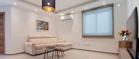 A modern living room with a sofa, coffee table, and a painting on the wall.