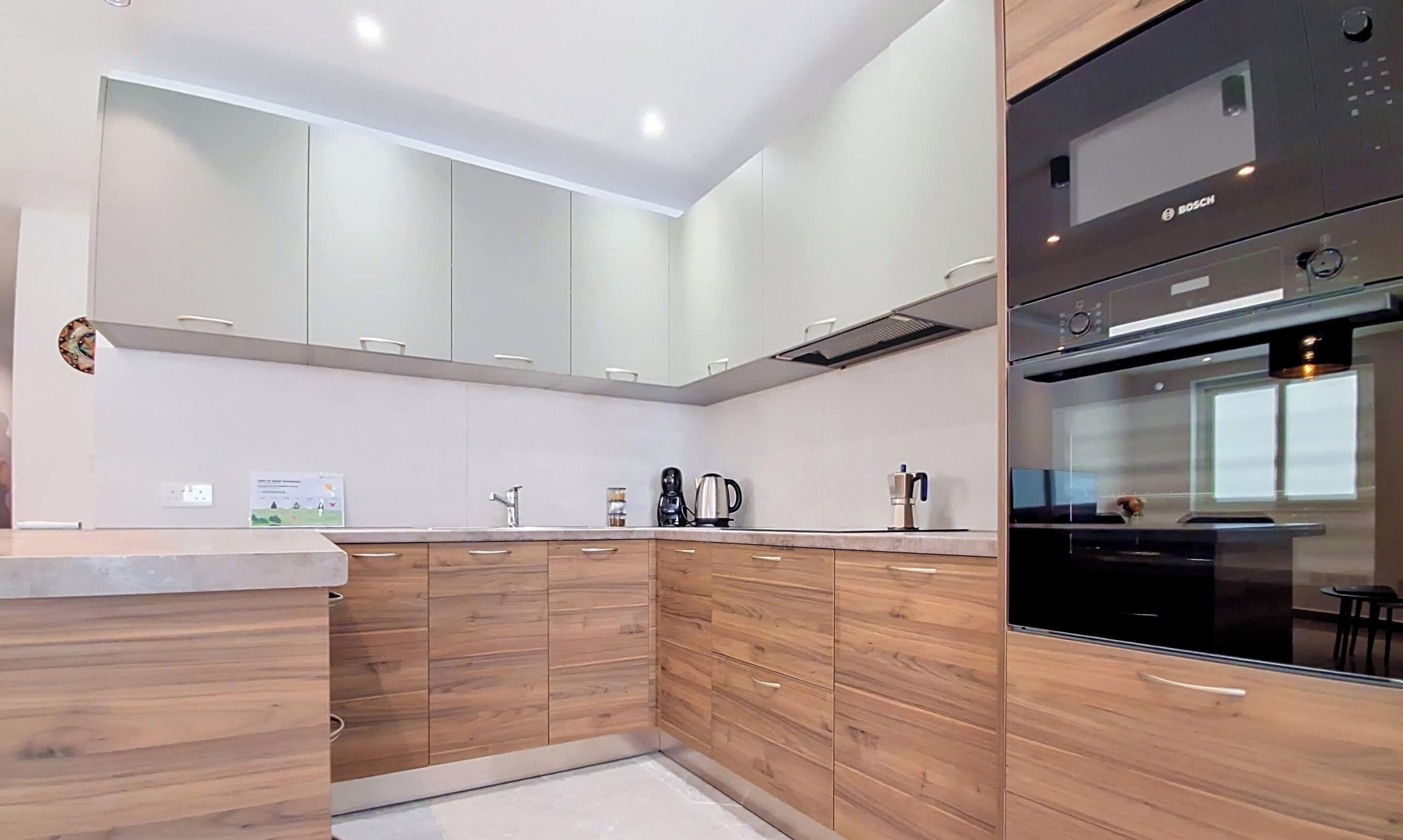 Una cocina moderna con gabinetes de madera, horno empotrado y campana extractora de acero inoxidable.