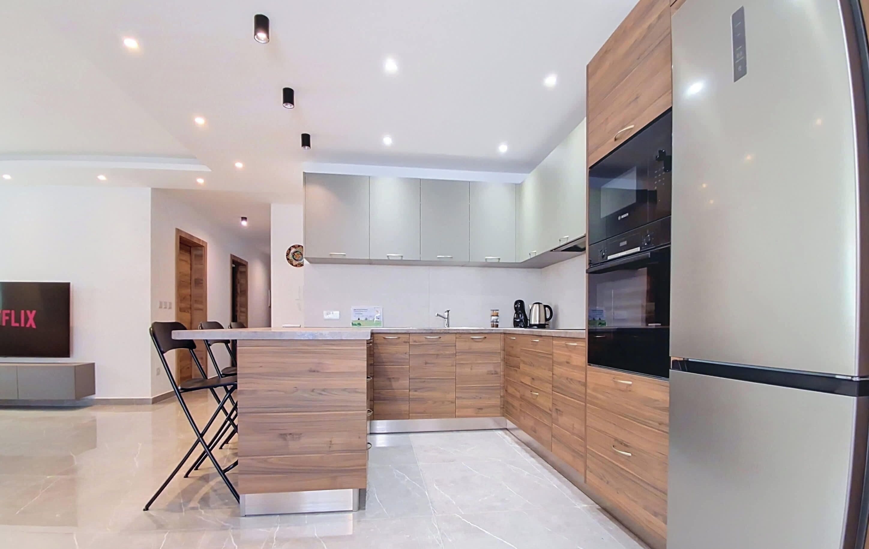 Una cocina moderna con armarios de madera, un refrigerador de acero inoxidable y una cafetera.