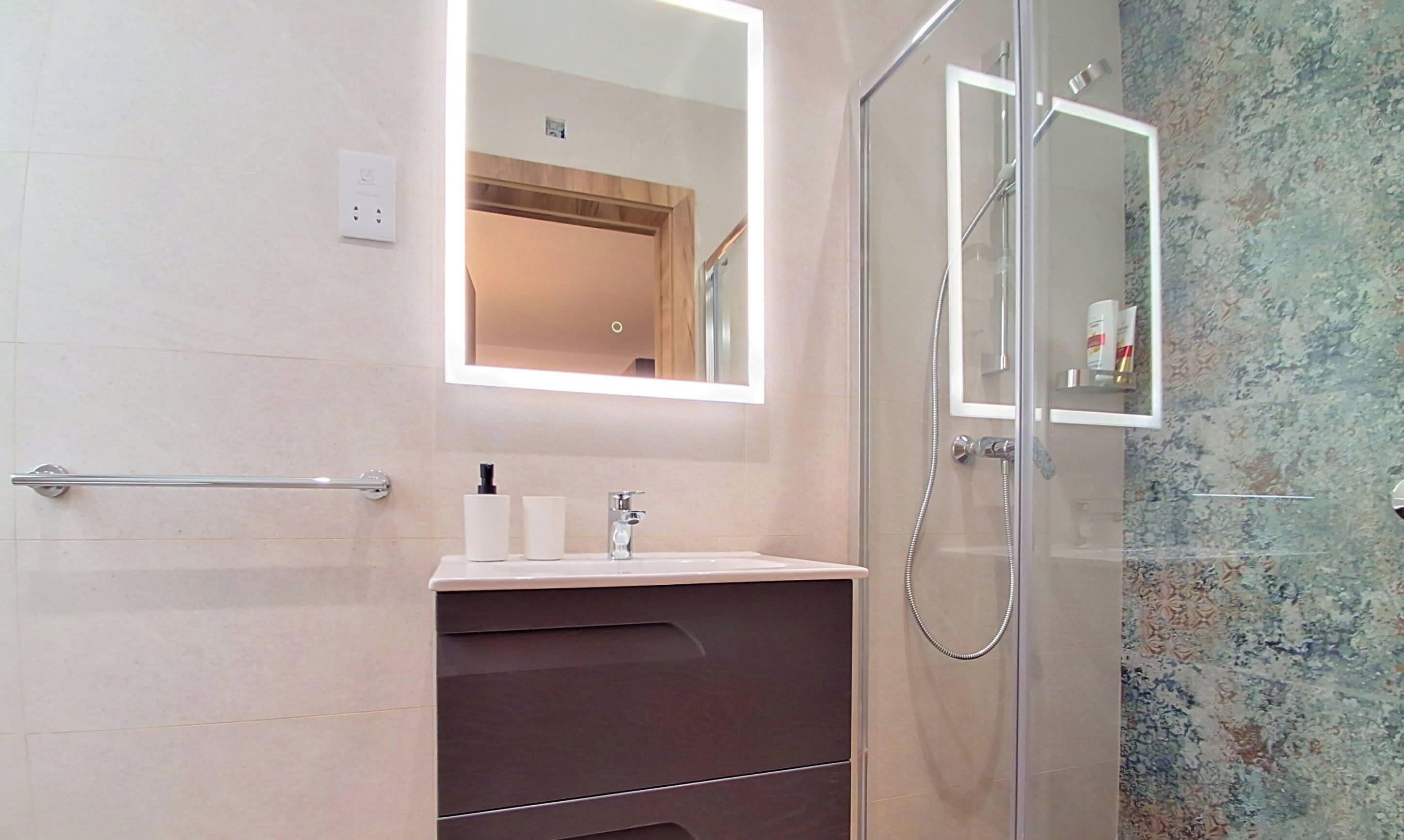 A modern bathroom with a glass shower enclosure, a vanity with a mirror, and a towel rack.