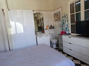 Ein Schlafzimmer mit Bett, Kommode, Toilette und Fernseher.