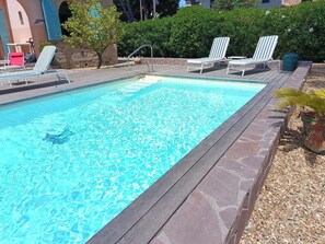 Ein rechteckiger Swimmingpool mit umlaufender Holzterrasse.