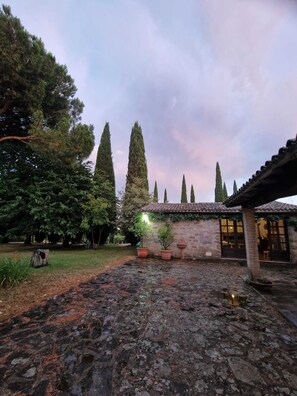 A courtyard with stone flooring, a brick wall, and tall cypress trees. - A charming historic farmhouse, 10 minutes from Orvieto, with a garden and private pool, (Umbria)