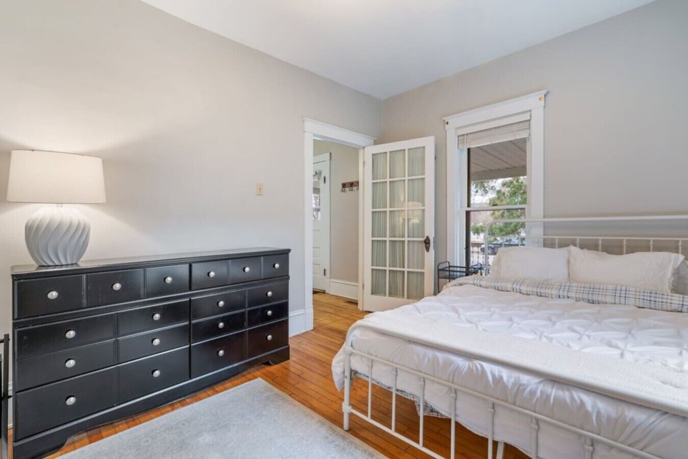 A bedroom with a bed, a dresser, and a lamp.