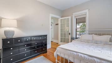 A bedroom with a bed, a dresser, and a lamp.
