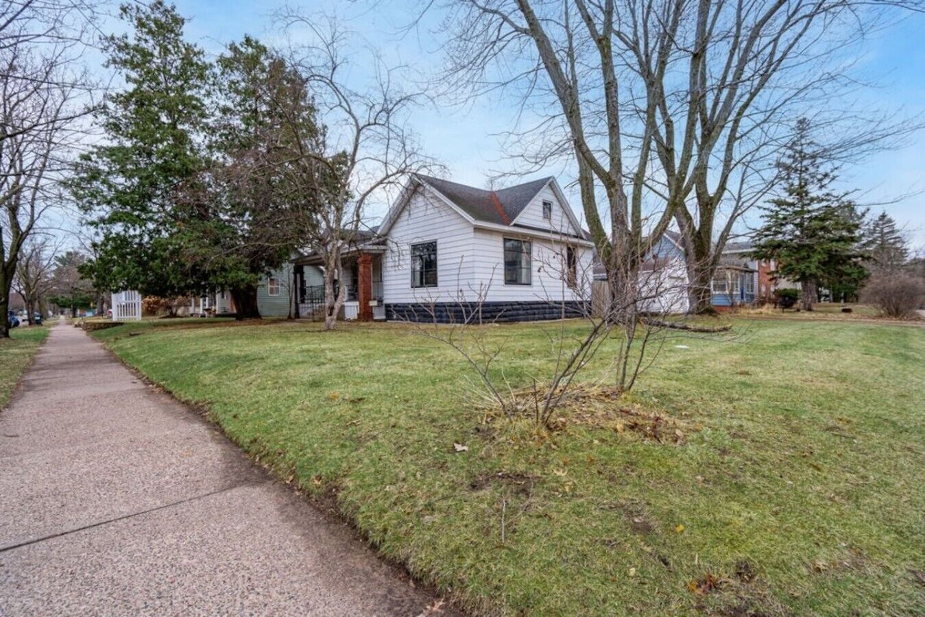Una casa residencial con patio delantero, acera y camino de entrada.