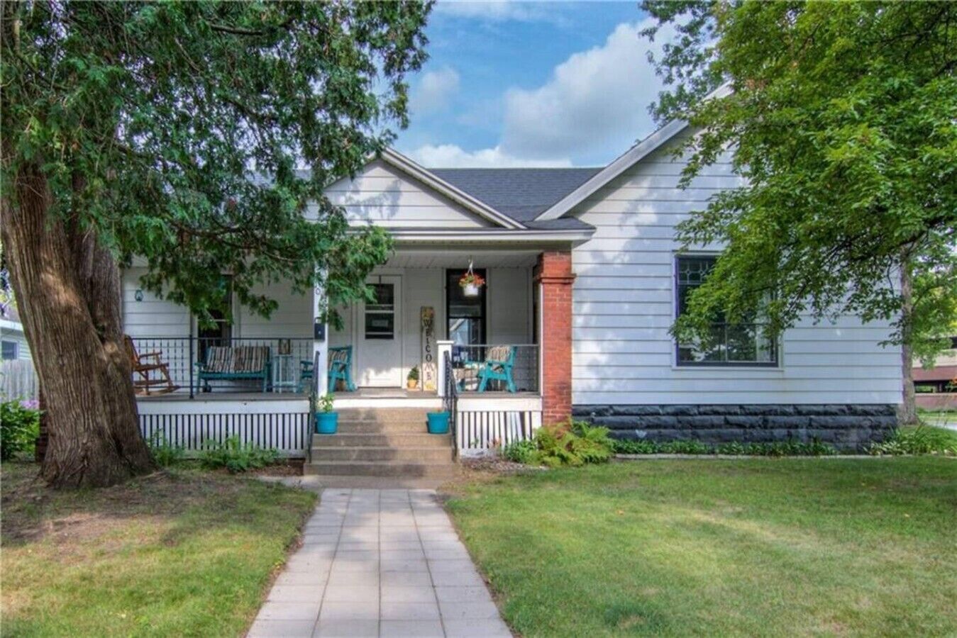A single-story house with a front porch, a brick column, and a pathway leading to the entrance.