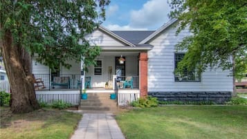 A single-story house with a front porch, a brick column, and a pathway leading to the entrance.