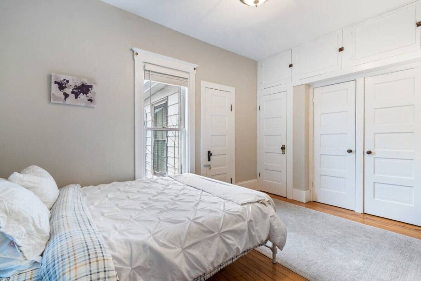 A bedroom with a bed, a window, and a door.