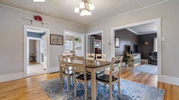 A dining area with a wooden table and chairs, a blue patterned rug, and a ceiling light fixture.