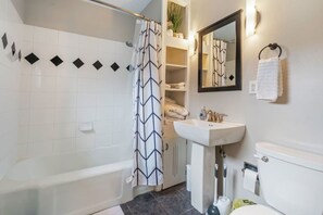 A bathroom with a bathtub, a sink, a toilet, and a mirror. - Charming 2 bedroom home next to Mayo (Eau Claire)