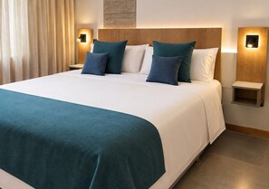 A hotel room with a large bed, two bedside tables, and a headboard with integrated lighting.