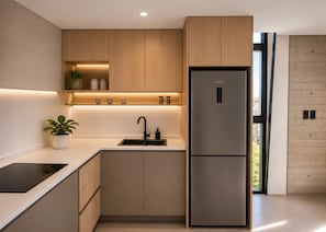 A modern kitchen with wooden cabinets, a stainless steel refrigerator, a sink, and a potted plant. - ONLY Design Suites & Spa (Mar de Las Pampas)