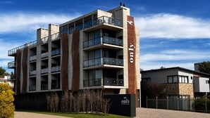 A multi-story hotel with a modern design, featuring balconies and a prominent logo on the facade.
