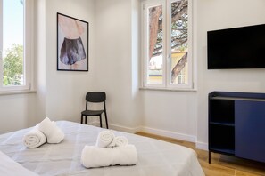 A hotel room with a bed, a chair, a TV, and a window with a view of trees. - Casa e Appartamento Vacanze Gallese 11 (Roma)