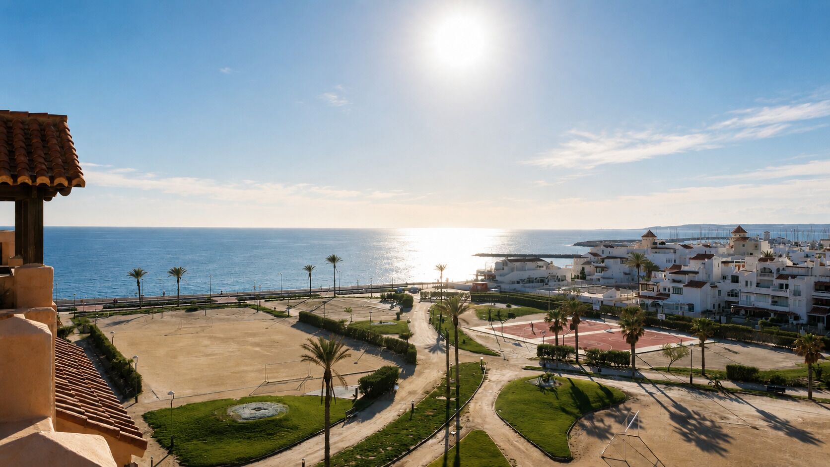 Une vue côtière comprenant une plage, des palmiers et un quartier résidentiel avec des bâtiments blancs.