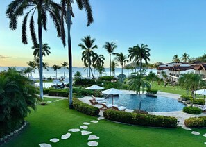 Ett semesterparadis med en swimmingpool, palmer och utsikt över havet.