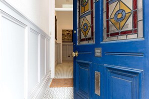 A blue door with a sign reading 'Stones Throw' and a patterned floor leading to a room with a painting on the wall. - Charming 2BR Flat on Grange-over-sands High Street (Grange-over-Sands)