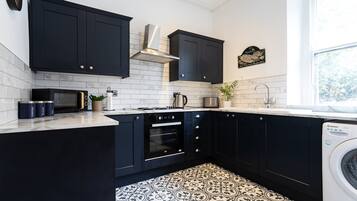 Una cocina moderna con armarios negros, horno empotrado, microondas y lavadora.