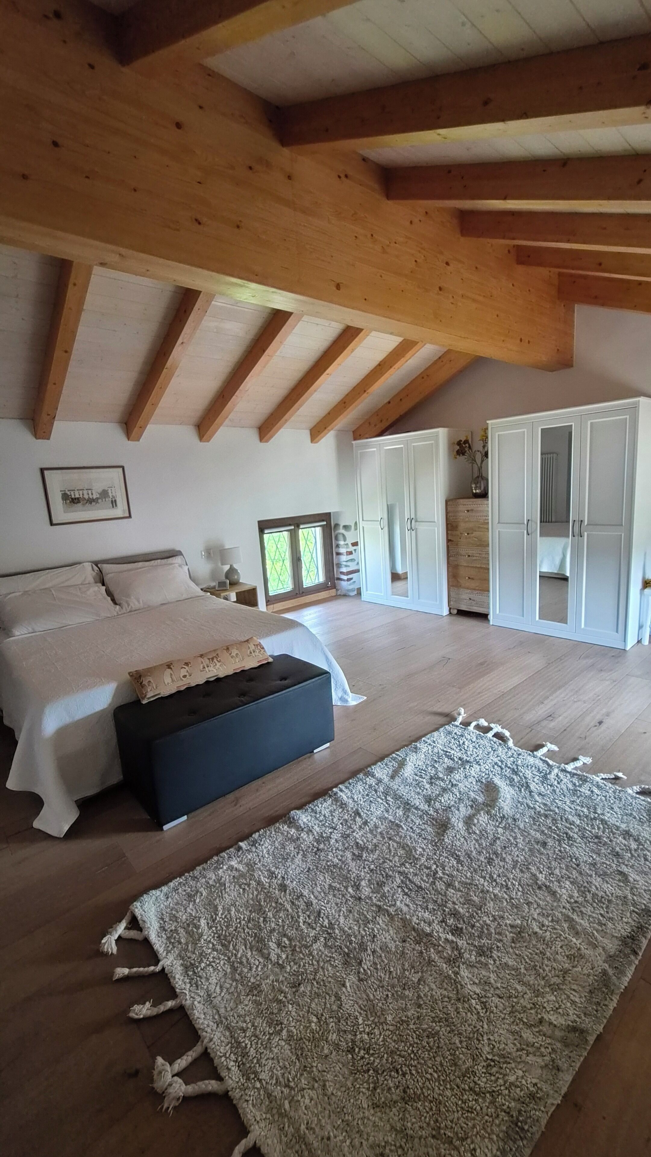 A bedroom with a bed, bedside tables, a wardrobe, and a large rug.