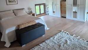 Et soveværelse med seng, natborde, et klædeskab og en stor måtte.