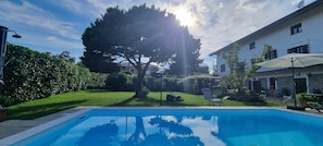 Una piscina con prato e alberi sullo sfondo.