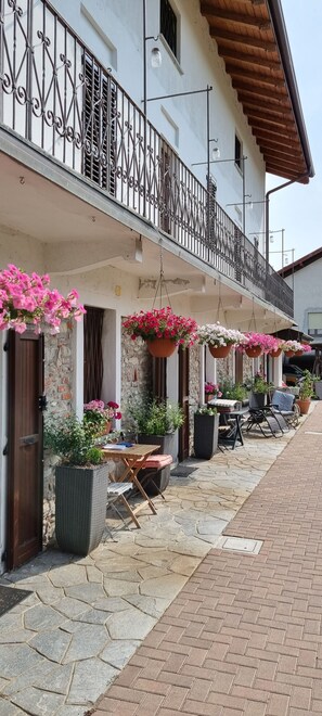 Un edificio con balcón, mobiliario exterior y macetas colgantes de flores.