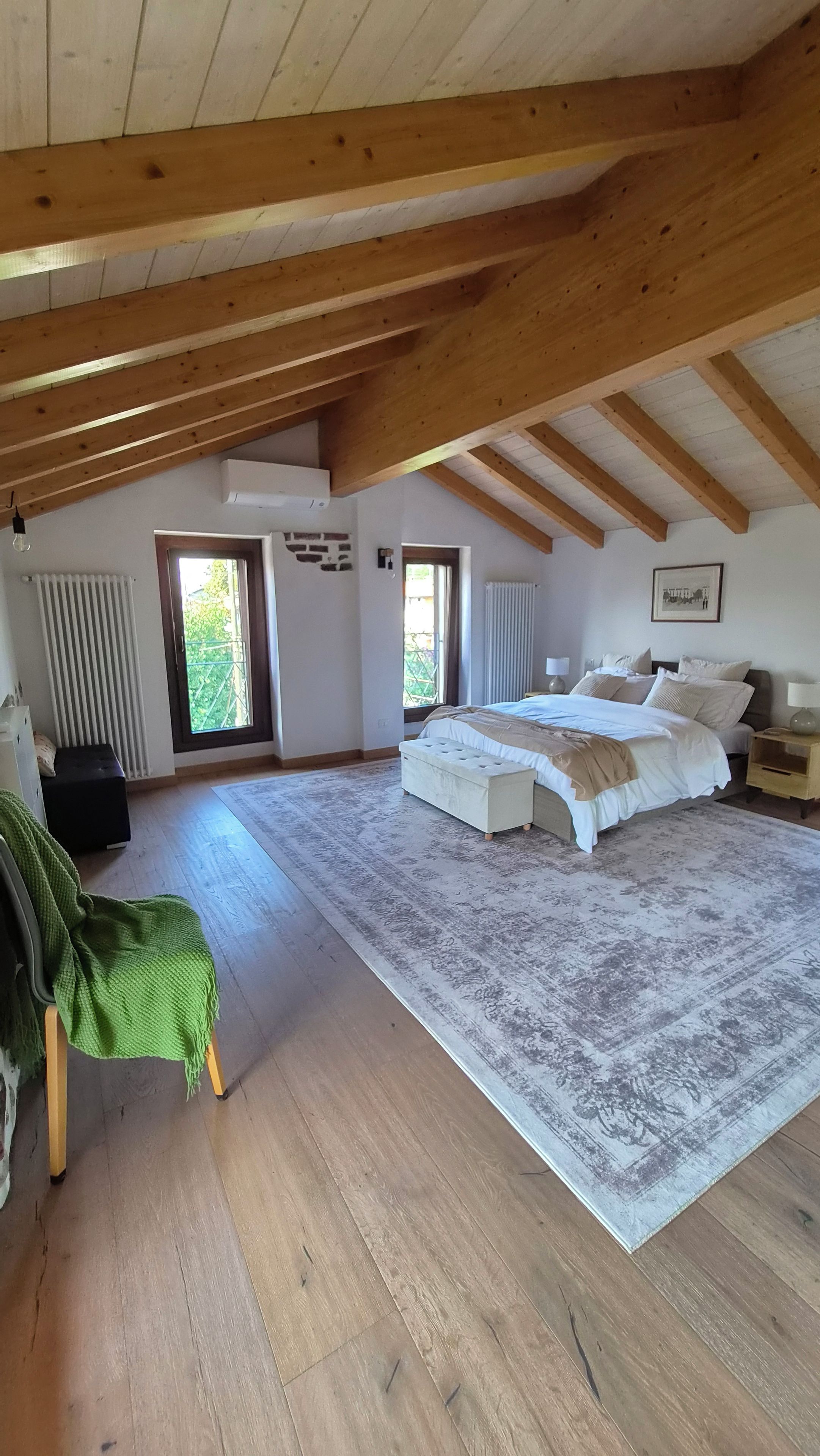 Un'ampia camera da letto con un letto grande, una panca e vista sull'esterno attraverso una finestra.