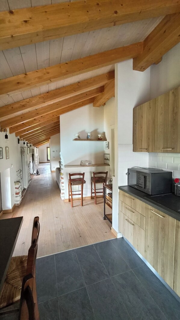 A kitchen with wooden cabinets, a microwave, and a dining area with chairs.