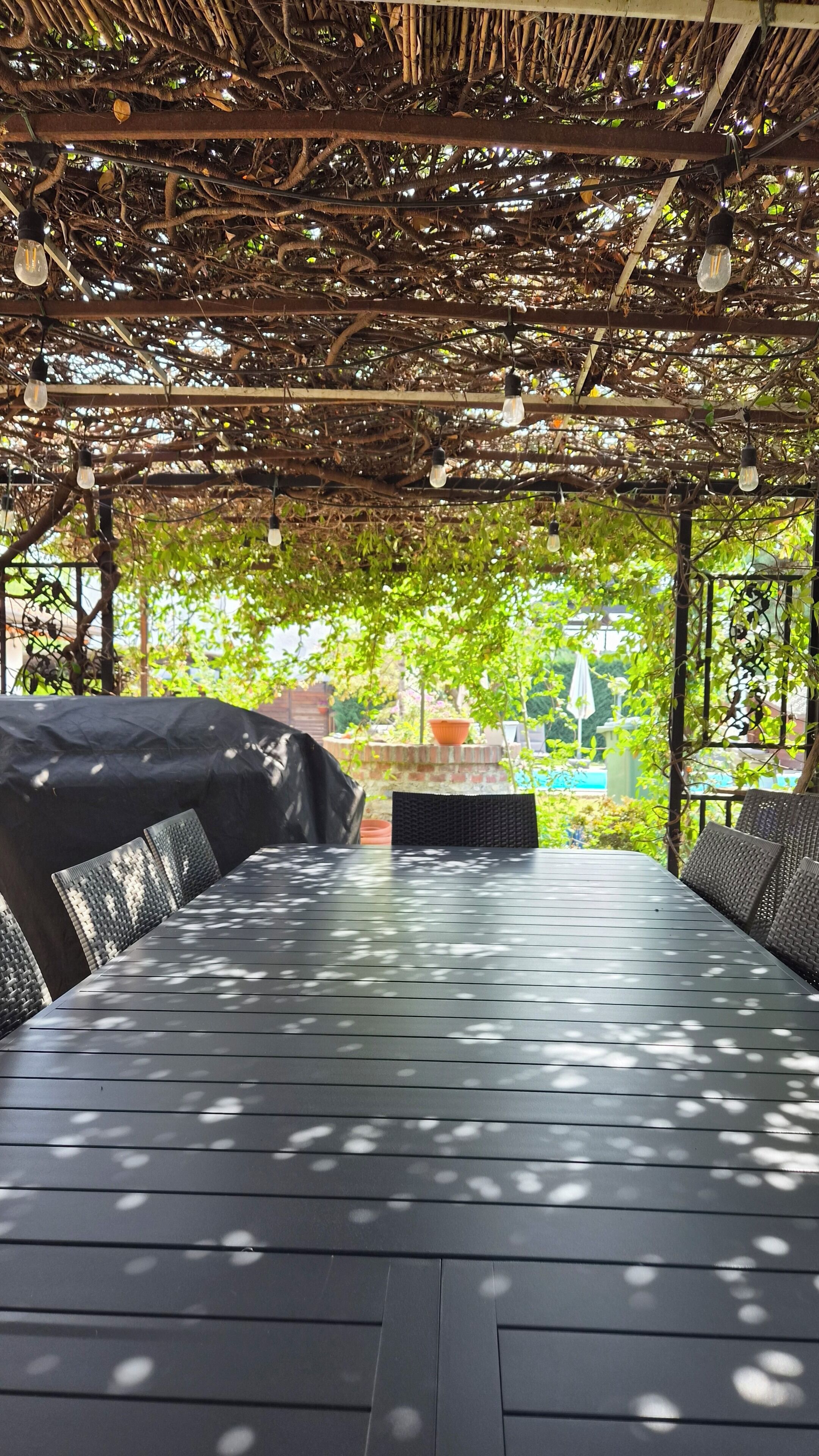 An outdoor seating area with a pergola overhead, a table, and chairs.