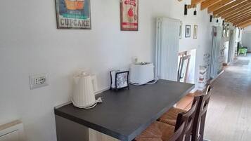 A kitchen with a wooden ceiling, a countertop, and bar stools. There is a poster on the wall and a light fixture above the counter.