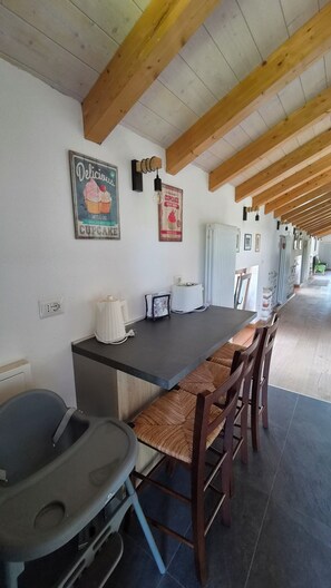 A kitchen with a wooden ceiling, a countertop, and bar stools. There is a poster on the wall and a light fixture above the counter.