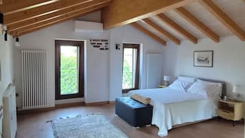 Ein Schlafzimmer mit einem großen Bett, einem Nachttisch, einem Fenster und Blick auf Grün.