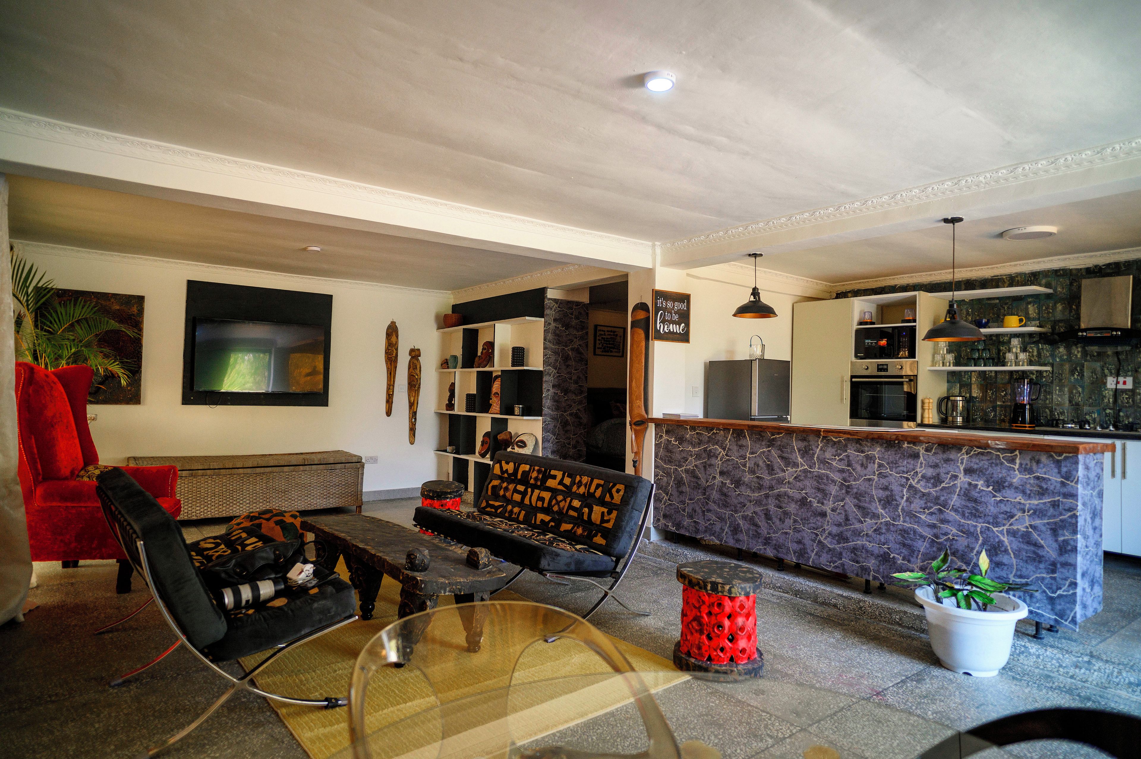 A modern living room with a glass coffee table, a red armchair, and a black sofa with patterned cushions.