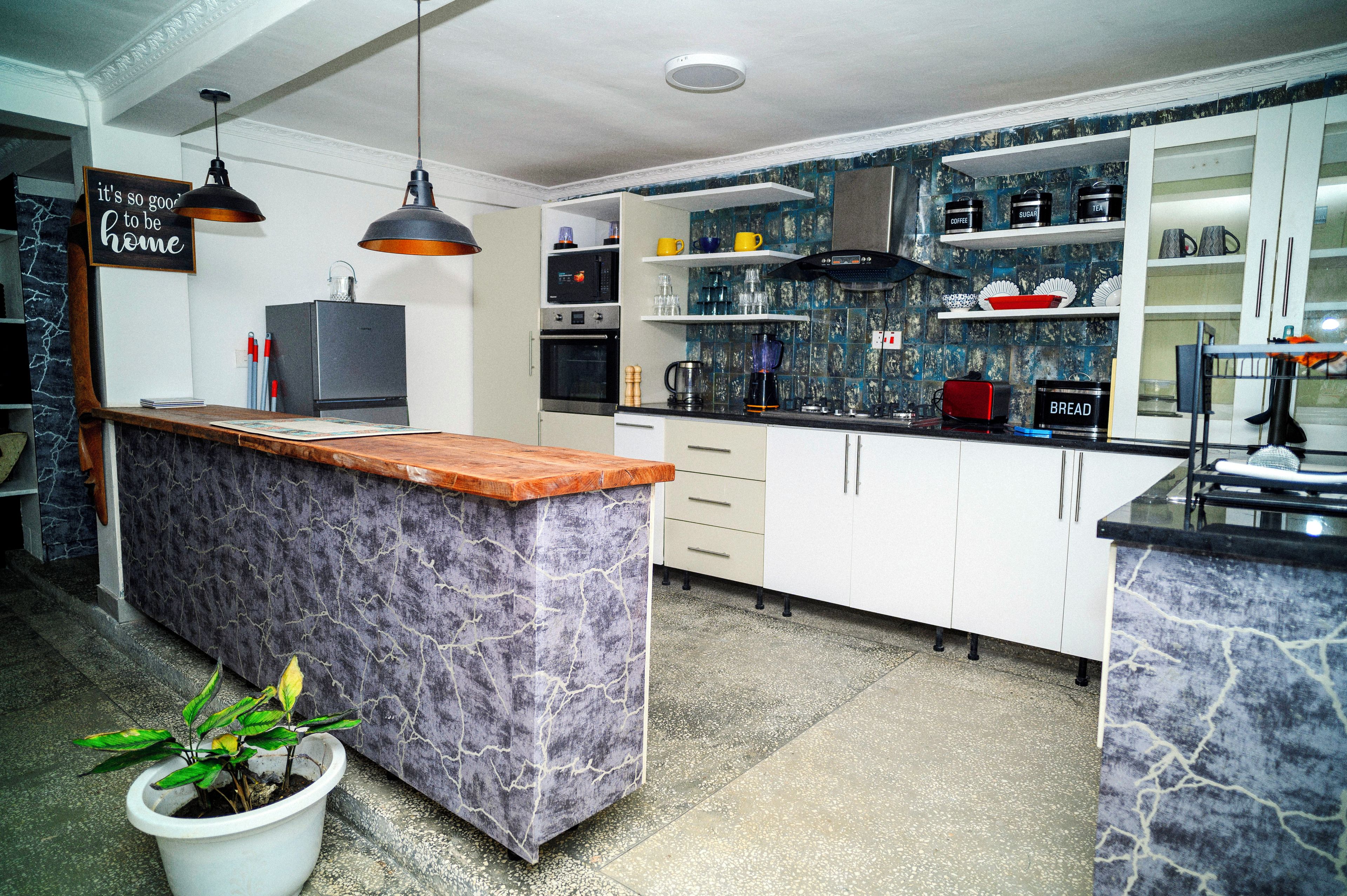 Une cuisine moderne dotée d’un îlot central avec un comptoir en marbre, d’appareils électroménagers intégrés et d’une enseigne décorative.