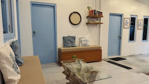 Una habitación con un banco de madera, una mesa de centro de vidrio, un reloj de pared y una estantería.