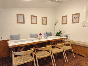 Un coin repas avec une table en bois, quatre chaises et des œuvres d’art encadrées accrochées aux murs.