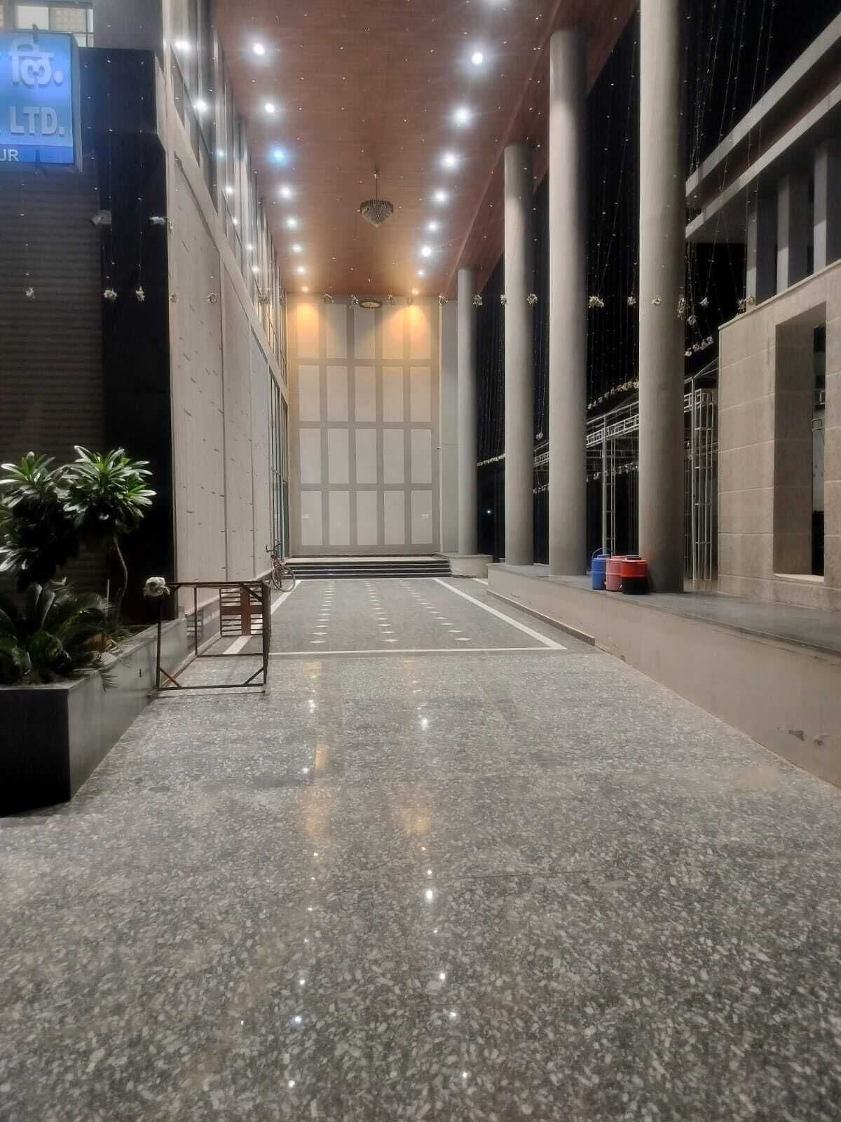 A spacious indoor area with a polished floor, large columns, and a ceiling with numerous lights.