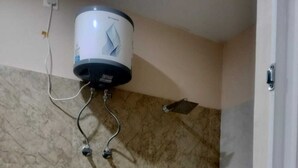 Un baño con pared de mármol, calentador de agua instalado en la pared y zona de ducha.
