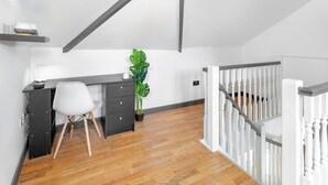 Ett modernt sovrum i loftstil med ett skrivbord, en stol och en stor växt.