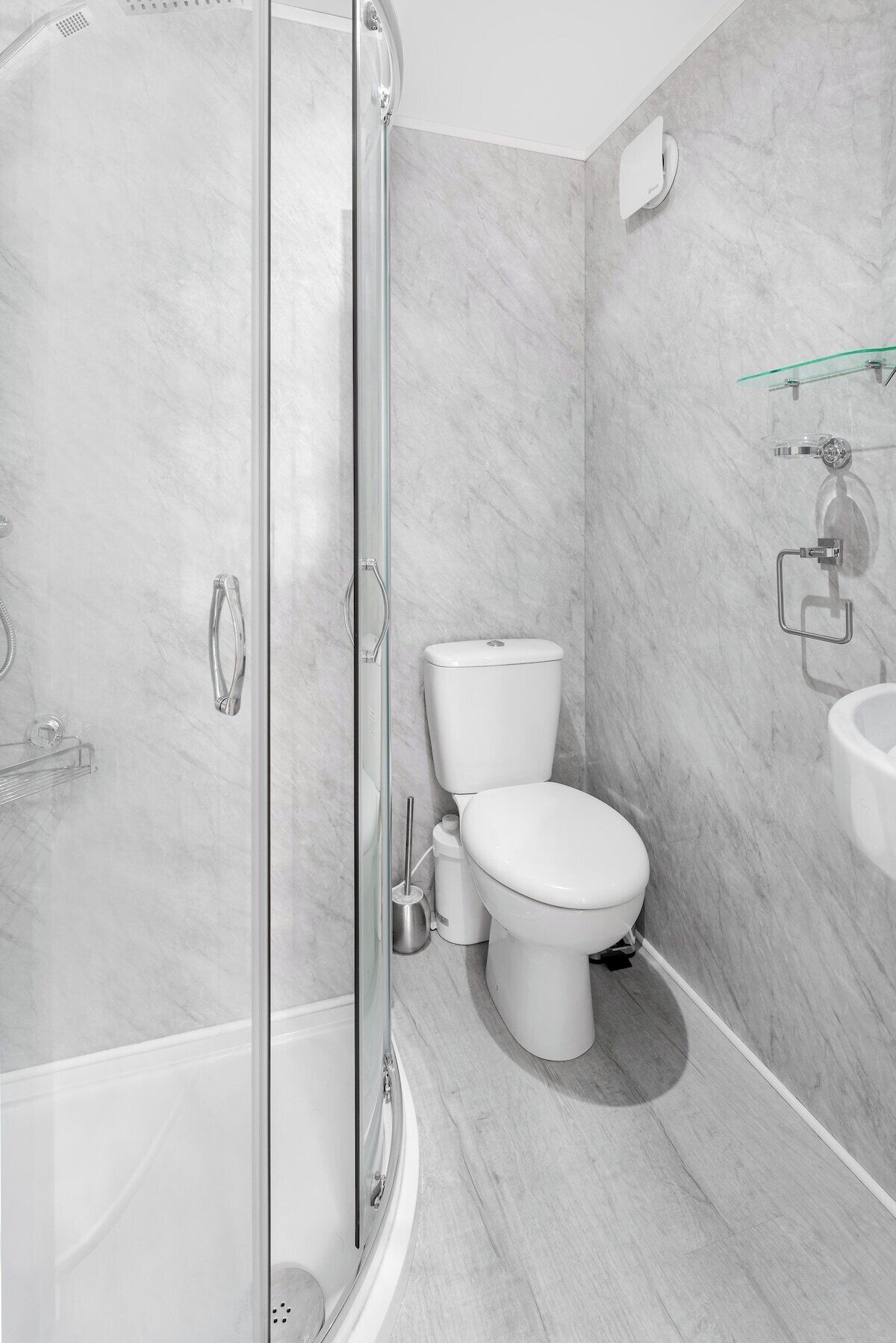 Un bagno moderno con doccia vetro, servizi igienici e lavandino.