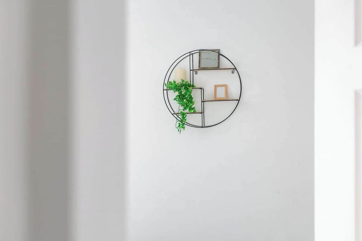 A wall-mounted circular decoration with a plant, a picture frame, and a candle.
