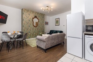 Ett kompakt bostadsutrymme med en matplats, soffa och ett litet kök.
