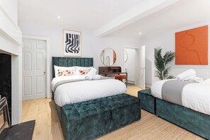 Ein Schlafzimmer mit einem großen Bett, zwei Nachttischen, einem Spiegel und einem Kamin.