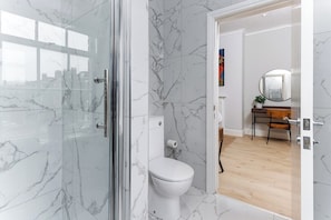 Ein modernes Badezimmer mit einer Duschkabine aus Glas, einer weißen Toilette und einem Holzboden.