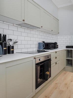 A modern kitchen with white tiled backsplash, stainless steel appliances, and light-colored cabinetry. - Flatzy - City Centre Mansion | Sleeps 22 | 5 Baths (Liverpool)