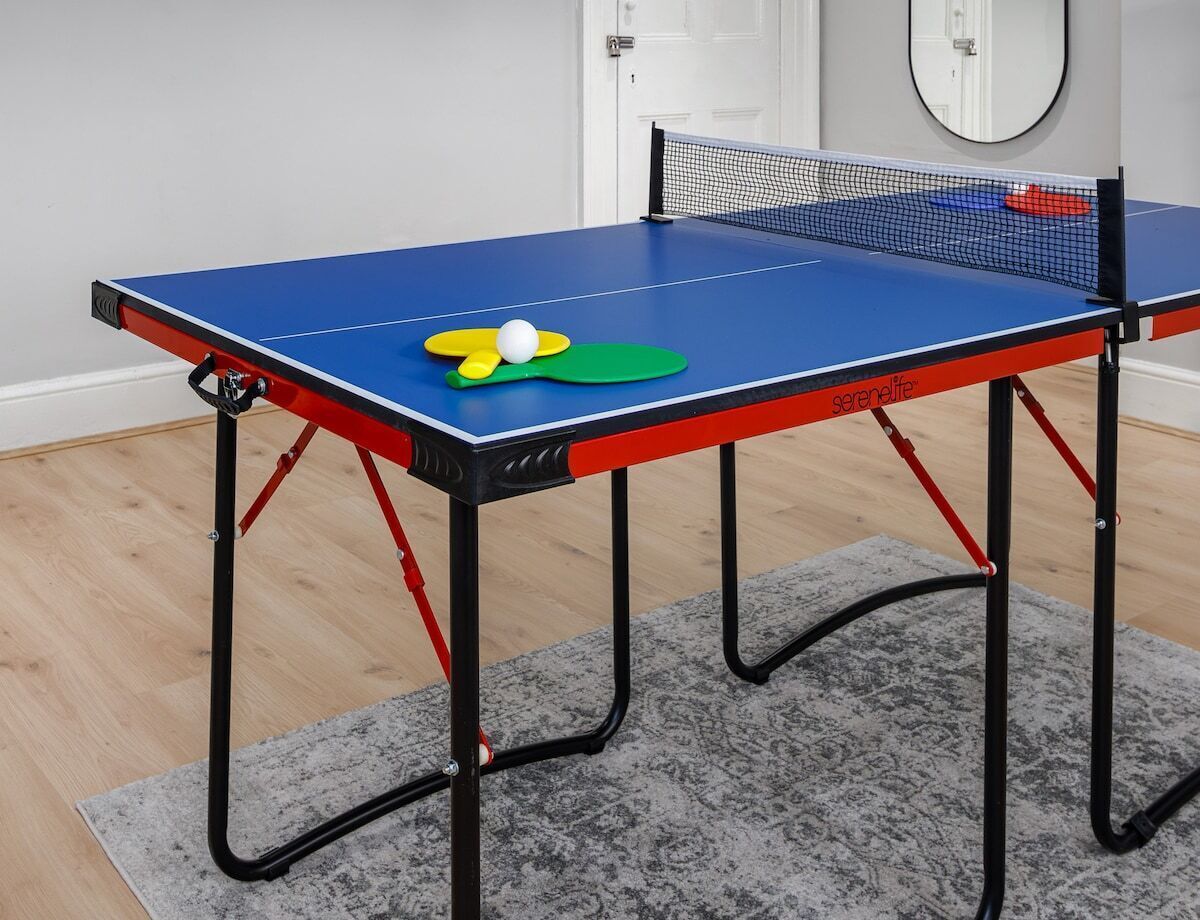 A ping pong table with a net, a ball, and paddles.